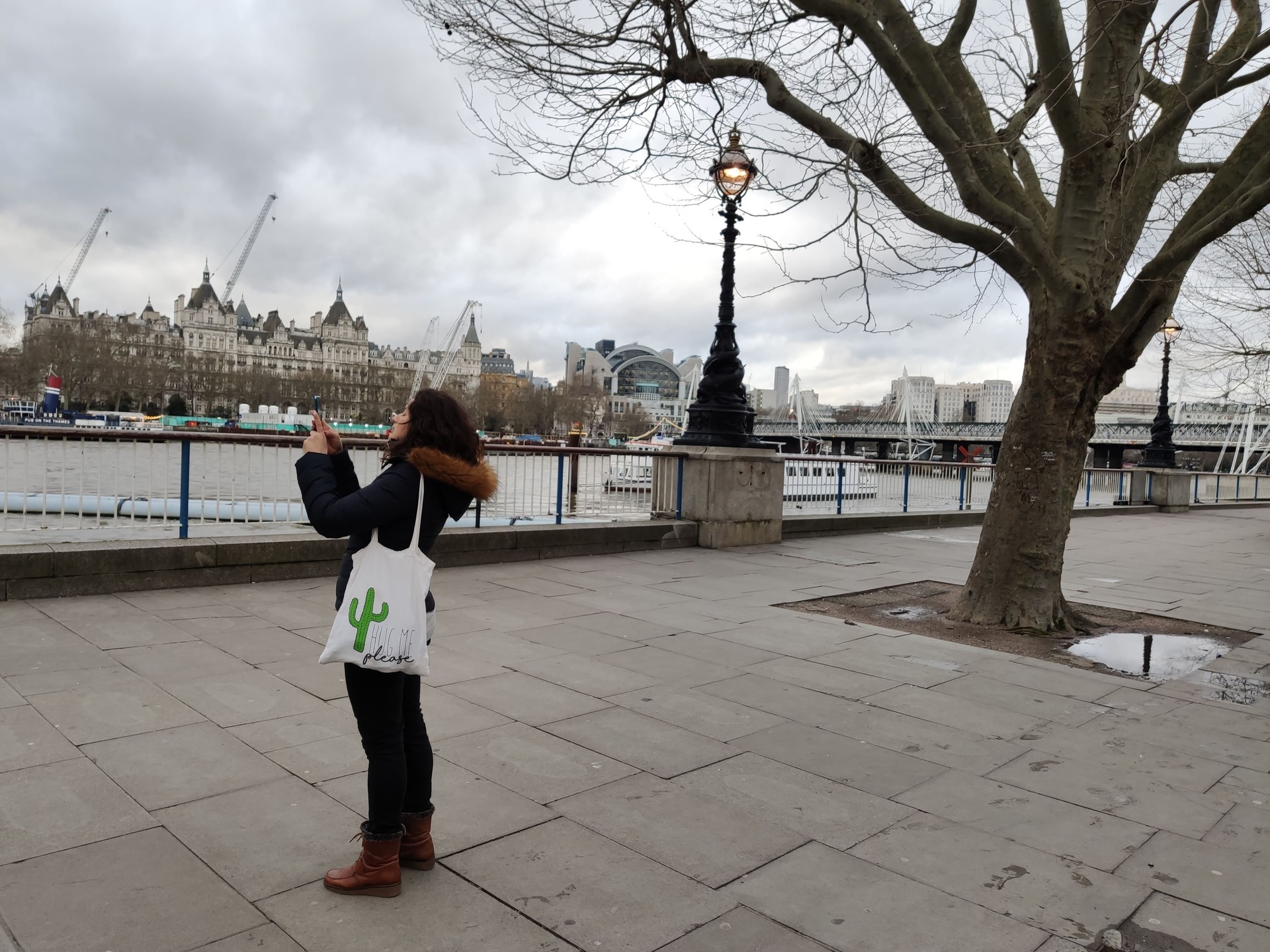 Woman taking a picture of the River Thames with her smartphone