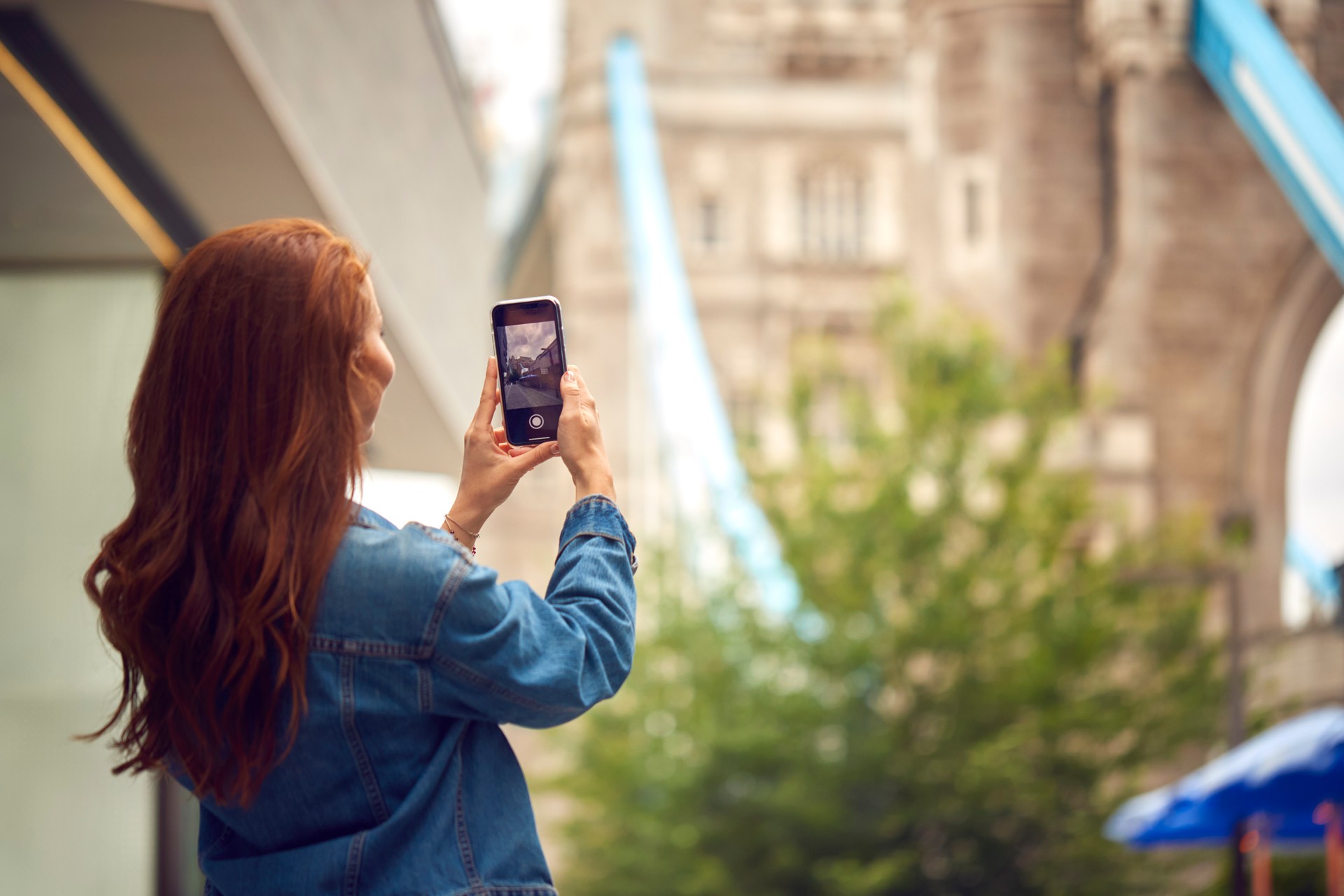 Female Vlogger Or Social Influencer In London Taking Photo On Mobile Phone Of Tower Bridge